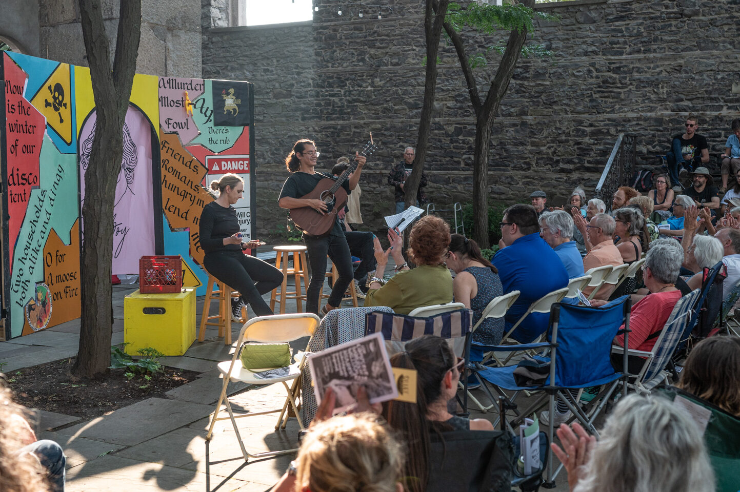 People singing, performing, and playing guitar to a mass of people.