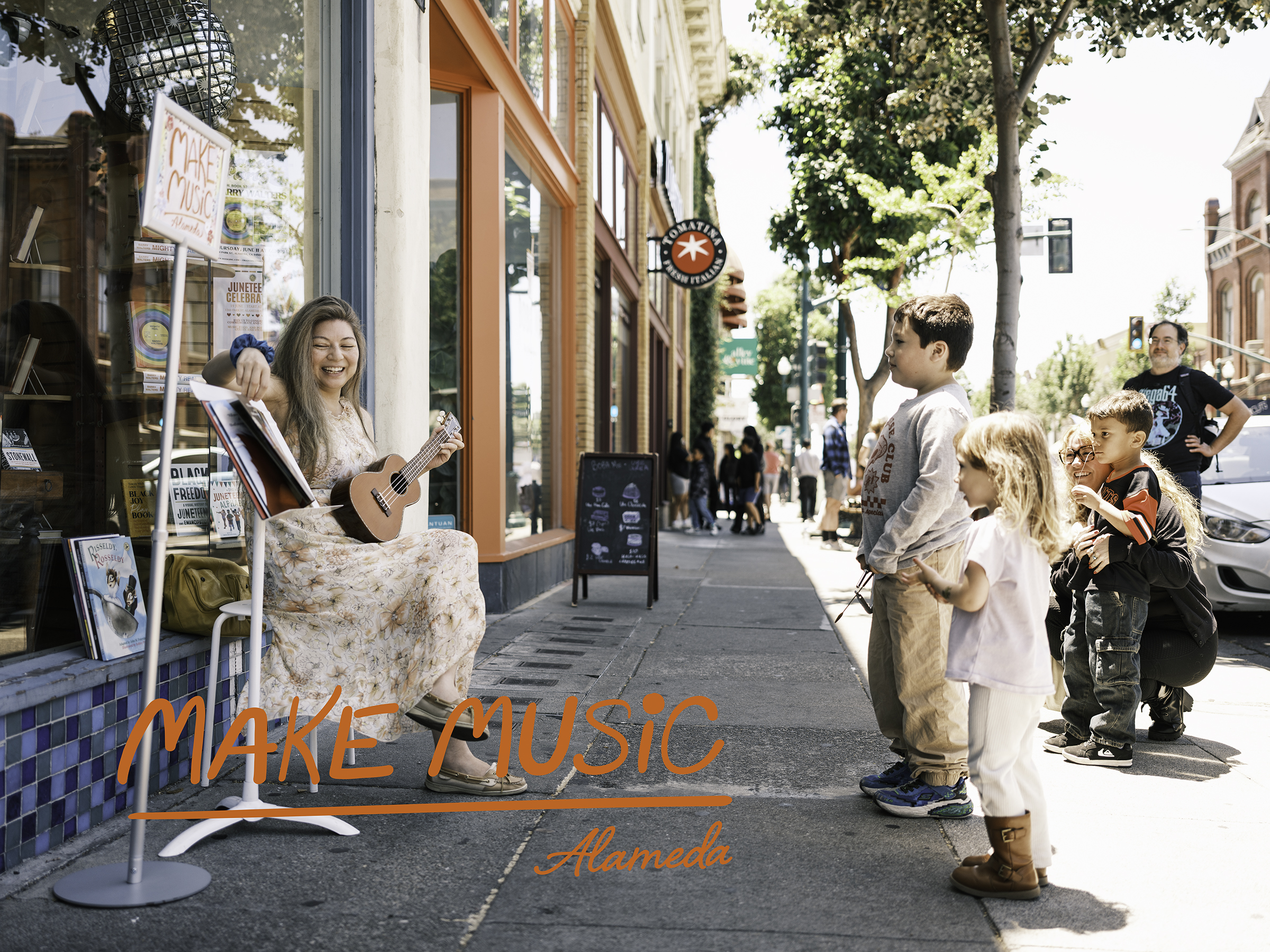 Katherine Park sings song stories on the sidewalk with her ukulele while children look on at Books Inc. Alameda. Photo by Douglas Despres